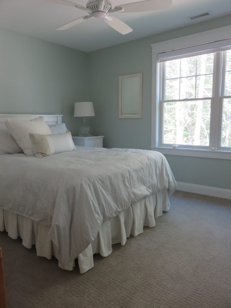 A bedroom with beige carpeting and pale blue walls