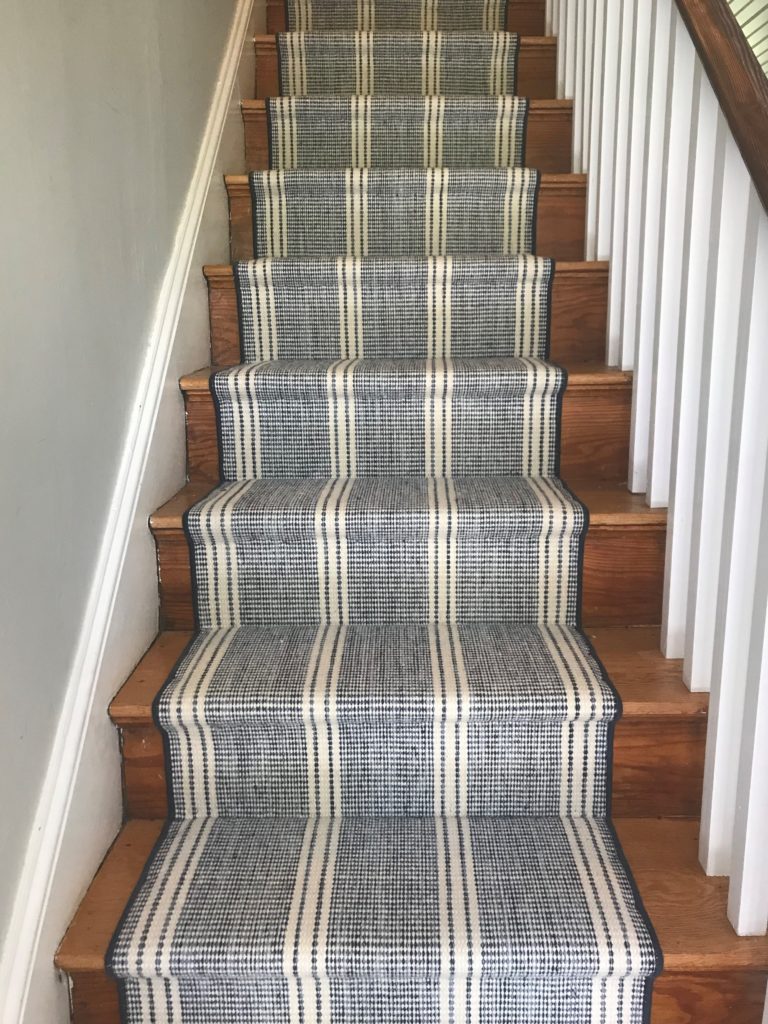 Blue and white patterned stair runner over dark brown stairs